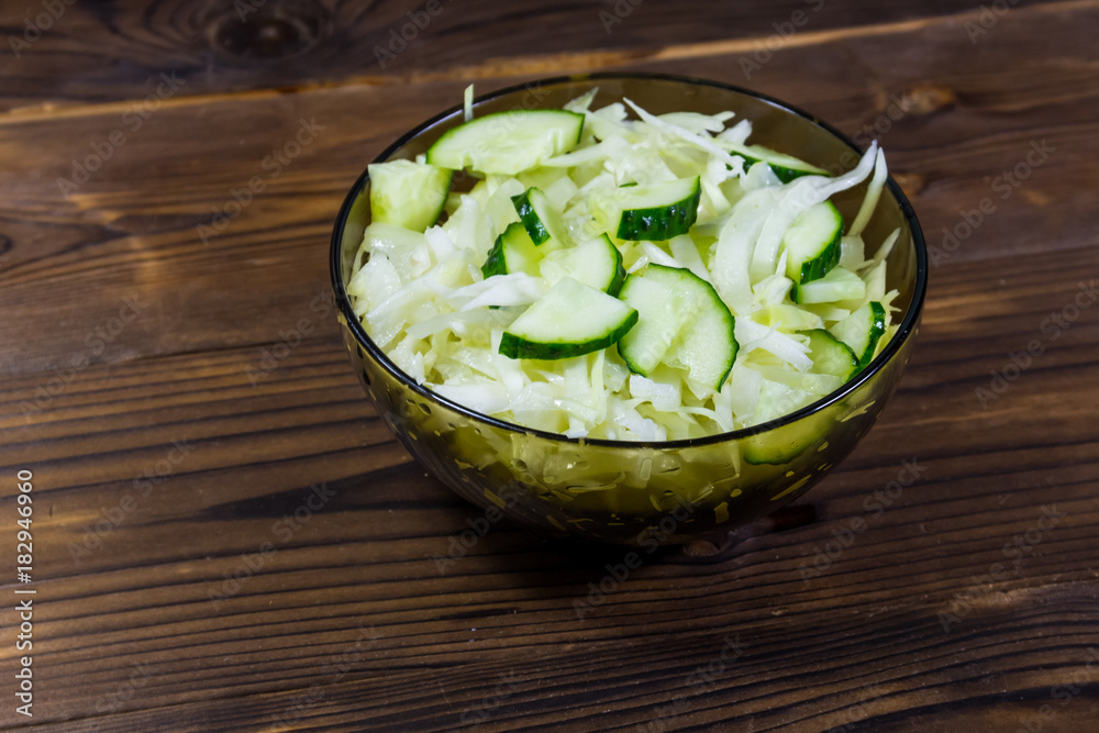 Spring vegan salad with cabbage and cucumber on wooden table Spring vegan salad with cabbage and cucumber on wooden table