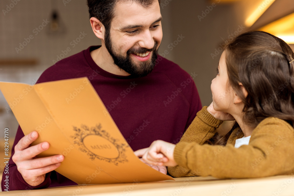 daughter showing father something in cafe menu daughter showing father something in cafe menu