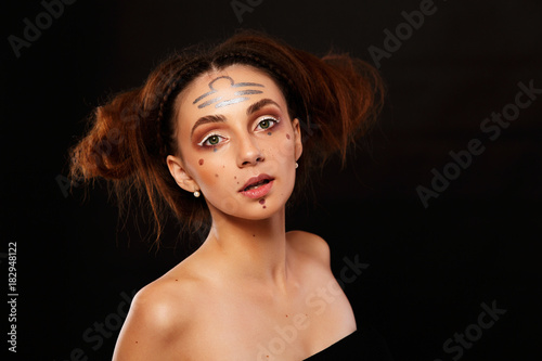 Stunning woman looks like an Aries with dark makeup and prints on her face