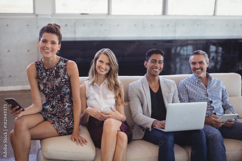Portrait of happy business people sitting together on sofa while