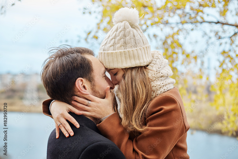 Loving couple walking in Park in autumn hugs and kisses. Autumn walk men and women in the woods on the fallen leaves. Romance and love on an autumn landscape