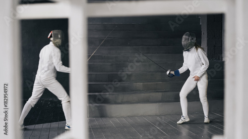 Two fencers man and woman have fencing match indoors © silverkblack