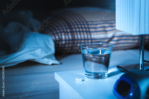 Fotografia Sleeping pill on nightstand next to a glass of water