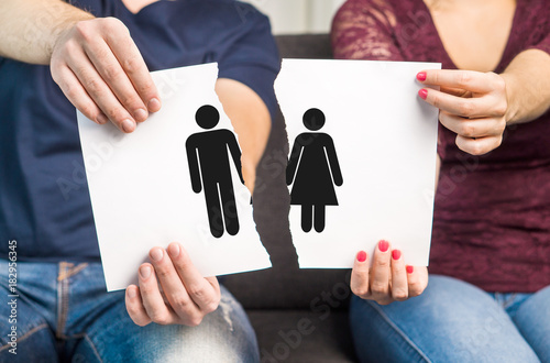 Break up, divorce and marital problems concept. Couple holding ripped pieces of paper with man and woman symbol.
