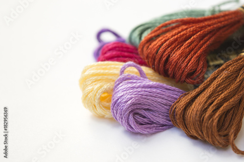 Pile of cotton embroidery floss on white surface close up, twisted threads for needlecraft, handmade background