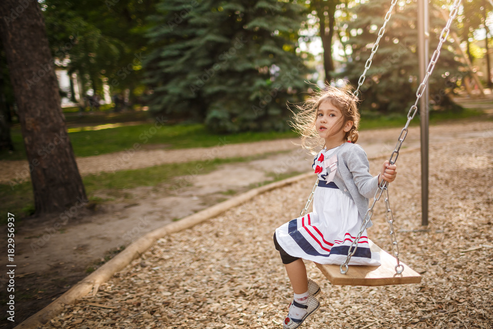 Cute little girl on a swing. Smiling child playing outdoors in summer. Cute little girl on a swing. Smiling child playing outdoors in summer.