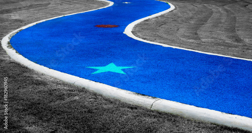 Blue abstract road with green star paint and gray grass as background