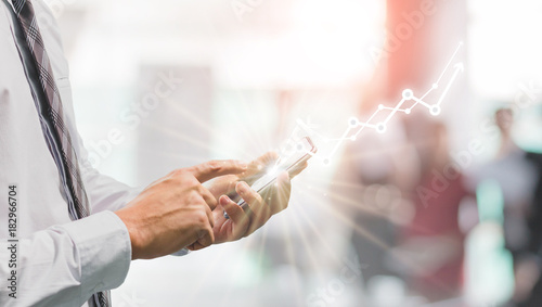 Success business man using smart phone on window with city building background and copy space.Concept of business people use technology.