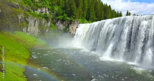 Mesa Falls Idaho - Drone Aerial Approaching View Of Wide Waterfalls Surrounded By Green Pine Trees With A Rainbow photo