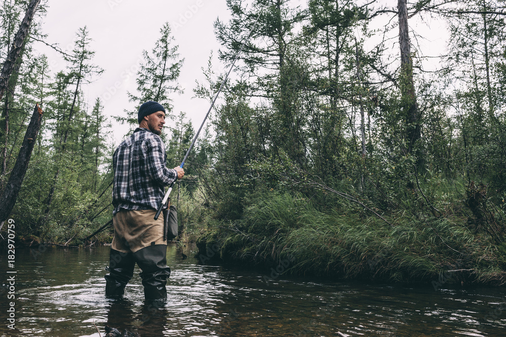 Angler standing in river with waders Angler standing in river with waders