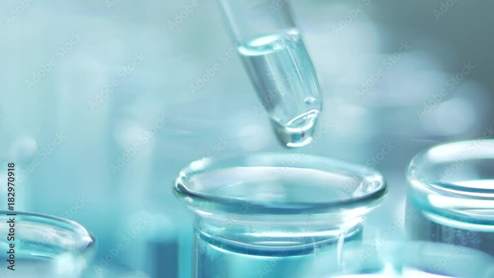In a laboratory, a scientist with a pipette analyzes a blue liquid to extract the DNA and molecules in the test tubes. Doctor working with liquid. In a laboratory, a scientist with a pipette analyzes a blue liquid to extract the DNA and molecules in the test tubes. Doctor working with liquid.