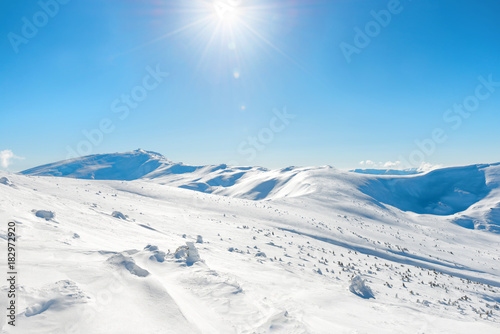 White winter mountains with snow and bright shining sun and sunrays