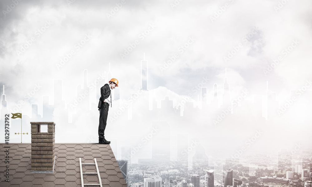 Engineer man standing on roof and looking down. Mixed media Engineer man standing on roof and looking down. Mixed media