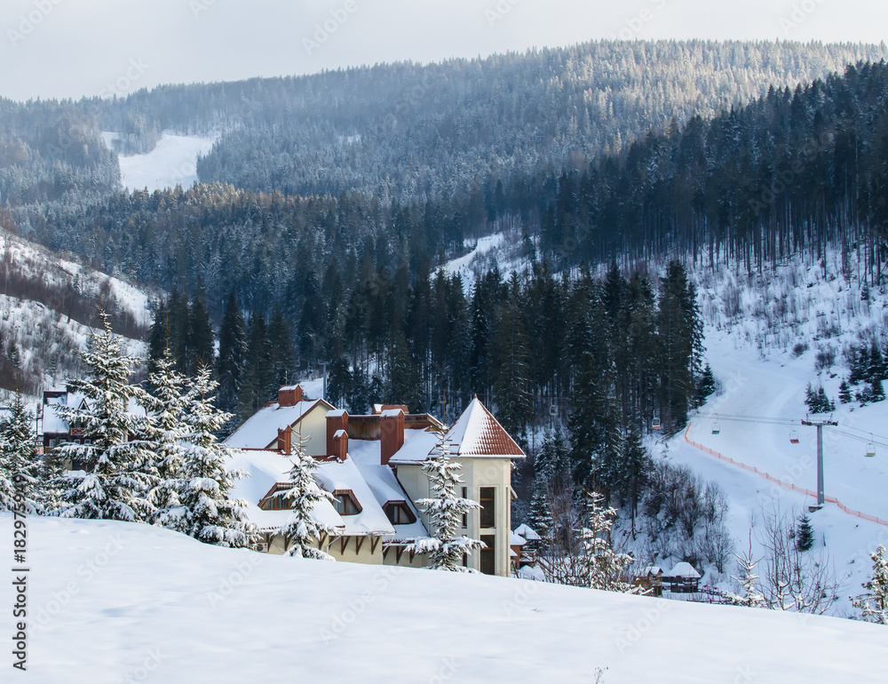 A snow-covered hotel with red roofs, facing the ski track. Carpathian mountains. Ukraine