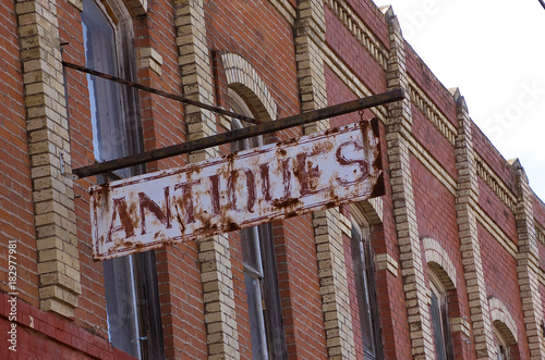 Antique metal rusty sign outside of old brick buildings in business district