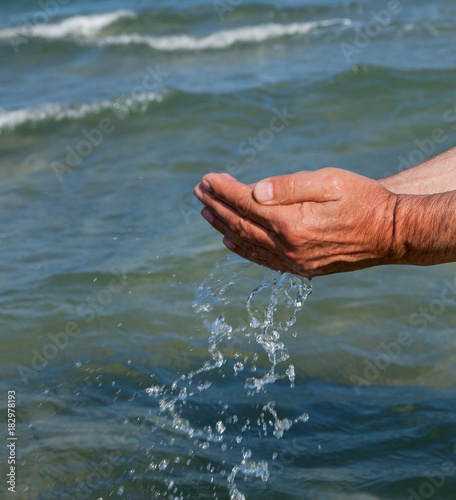 Photo of hands with sea water.