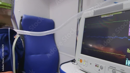 Ambulance car interior. Emergency medical service equipment. Patient on a stretcher receiving first aid. Close-up of screen of multiparameter patient monitor. Medical care and emergency transportation photo