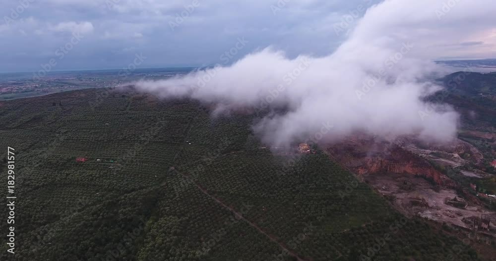Aerial, an overcast weather with a cloud on the hills with a lonely house, olive grove and a cave nearby Aerial, an overcast weather with a cloud on the hills with a lonely house, olive grove and a cave nearby
