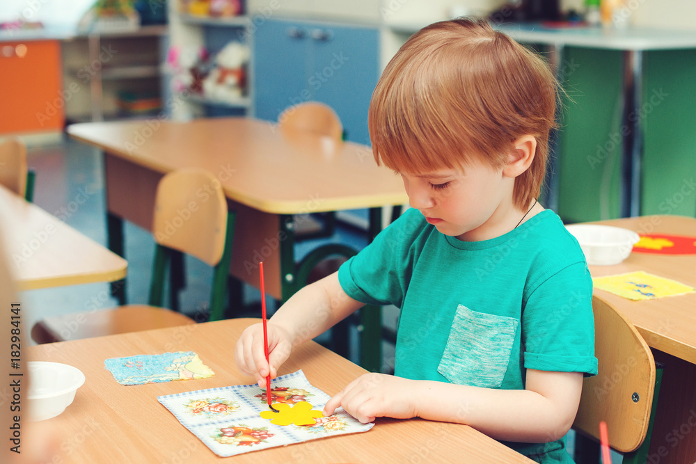 Fototapeta premium Cute little boy engaged in art and craft in classroom . Learning and education concept.