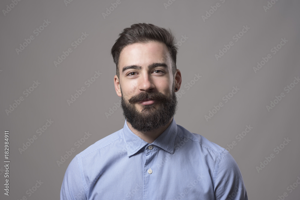 © sharplaninac - Horizontal head and shoulder portrait of young bearded business man smiling at camera against gray studio background. © sharplaninac - Horizontal head and shoulder portrait of young bearded business man smiling at camera against gray studio background.