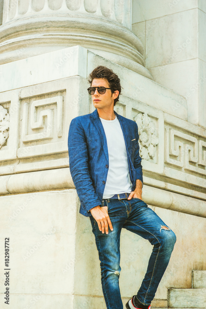 Man Casual Fashion. Dressing in blazer, under shirt, jeans, wearing sunglasses, a young European college student standing by column on campus in New York, looking away. . Stock-foto |