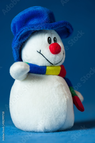 A cute little soft snowman with a blue hat and a colorful scarf © Stefan