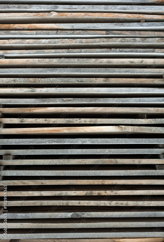 Folded wooden brown and gray planks in a sawmill. Piled alder boards as texture for design. Folded wooden brown and gray planks in a sawmill. Piled alder boards as texture for design.