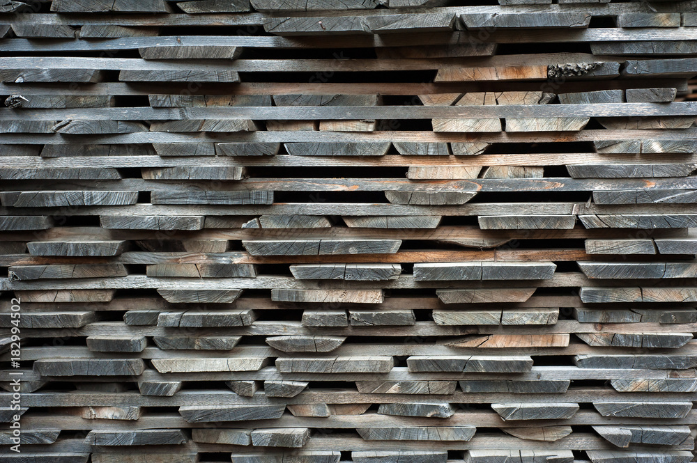 Folded wooden brown and gray planks in a sawmill. Piled alder boards as texture for design. Folded wooden brown and gray planks in a sawmill. Piled alder boards as texture for design.