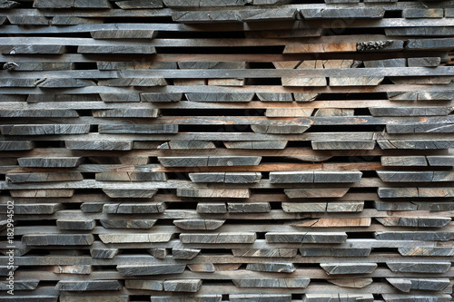 Folded wooden brown and gray planks in a sawmill. Piled alder boards as texture for design. © Viktoria