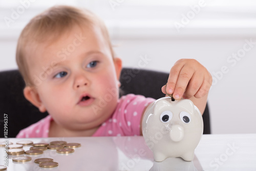 Baby Inserting Coin In Piggybank