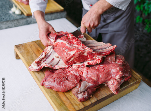 A man cook cuts meat with a knife in a restaurant.