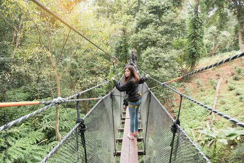 Asian woman enjoy travelling on hanging bridge in the forest, Doi Tung