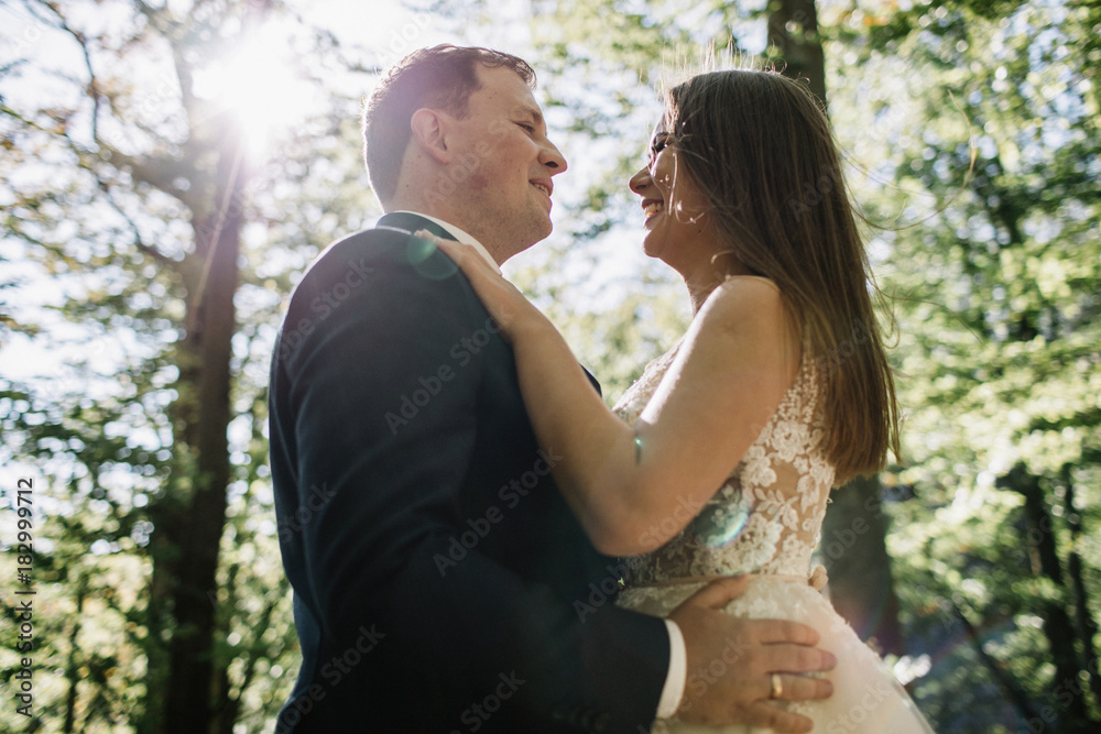 Young bride and groom walking high in mountains. Amazing weather with fog and sun