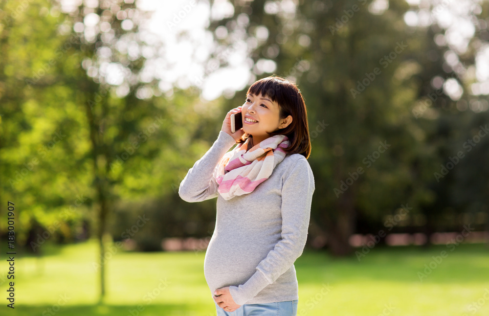 pregnant asian woman calling on smartphone at park pregnant asian woman calling on smartphone at park