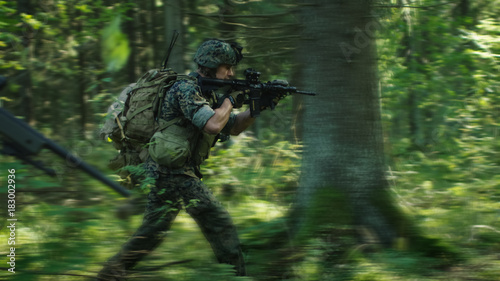 Squad of Fully Equipped Soldiers in Camouflage on a Reconnaissance Military Mission, Rifles in Firing Position. They're Running in Formation Through Dense Forest. Blurred Motion.