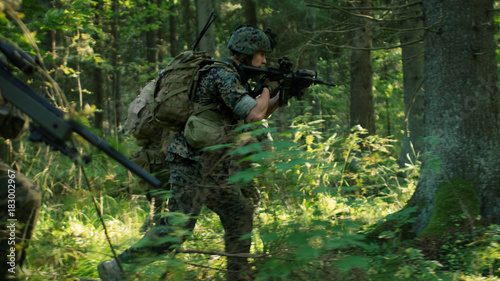 Fully Equipped Soldiers Wearing Camouflage Uniform Attacking Enemy, Rifles in Firing Position. Military Operation in Action, Squad Running in Formation Through Dense Forest.