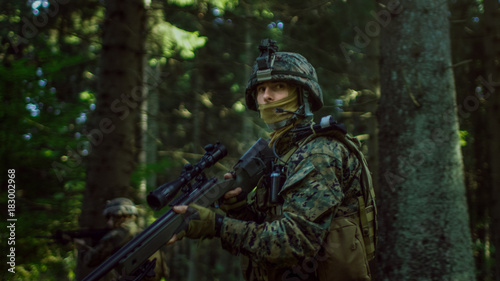 Fully Equipped Sniper Soldier Wearing Camouflage Uniform Attacking Enemy  Rifle in Firing Position. Military Operation in Action  Squad Running in Formation Through Dense Forest. Side View Long Shot.