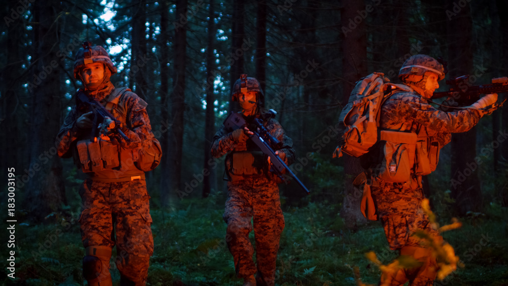 Squad of Five Fully Equipped Soldiers in Camouflage on a Reconnaissance Military Night Mission. They're Lit by Red Flare and Move Through Dense Forest.