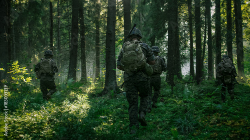 Fully Equipped Soldiers Wearing Camouflage Uniform Attacking Enemy, Rifles Ready to Shoot. Military Operation in Action, Squad Running in Formation Through Dense Smokey Forest. Back View Footage.