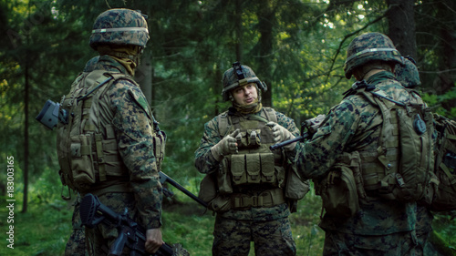 Squad Leader Discusses Military Operation Details with Soldiers, Commander Gives Orders. Fully Equipped and Armed Soldiers Ready for Mission in a Dense Forest.