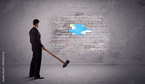 Business man hitting brick wall with hammer