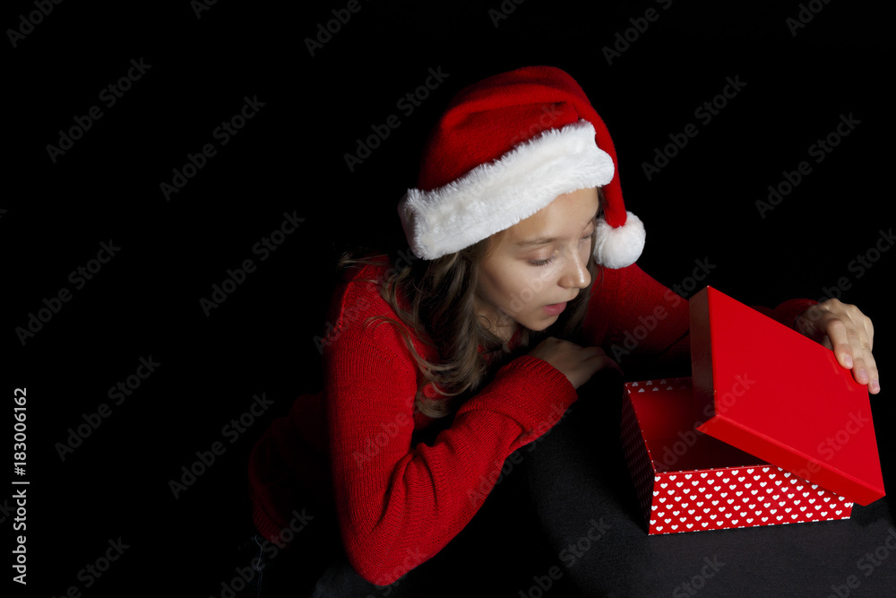Merry Christmas. A young girl in a red sweater and a Santa Claus hat holds a present - box and a hole in the middle. Merry Christmas. A young girl in a red sweater and a Santa Claus hat holds a present - box and a hole in the middle.