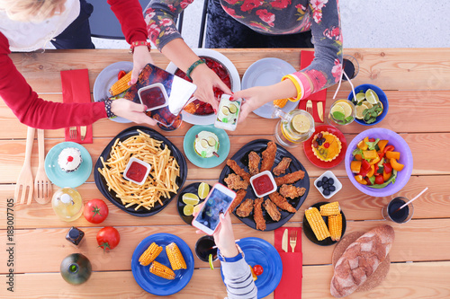 Top view of group of people having dinner together while sitting at wooden table. Food on the table. People eat fast food. Photograph food
