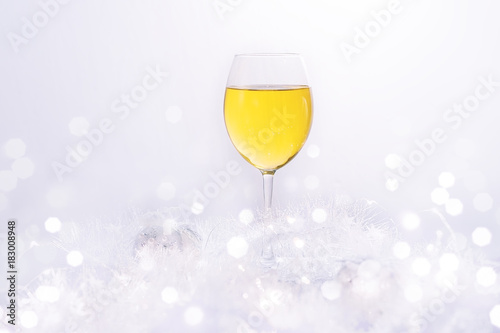 Wineglass of white wine on a white blurred background. Blurred bokeh light background, Christmas and New Year holidays background
