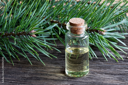 A bottle of pine essential oil with pine branches