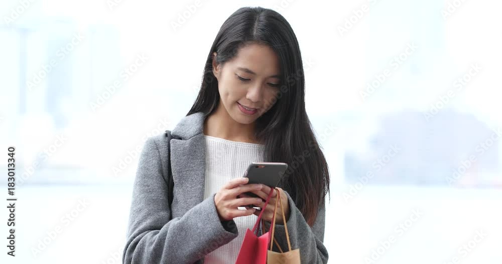 Asian woman holding shopping bag and use of mobile phone Asian woman holding shopping bag and use of mobile phone