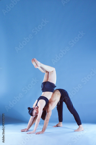 Young couple practicing acro yoga on mat in studio together. Acroyoga. Couple yoga. Partner yoga.