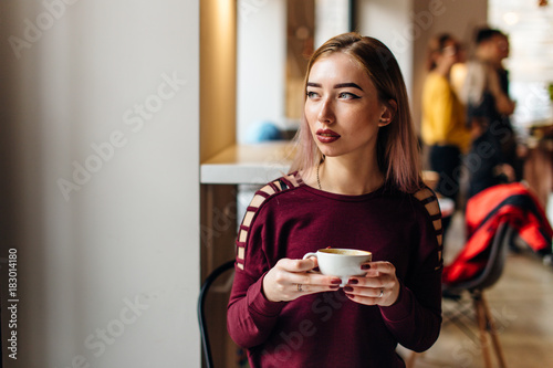 Young girl sit with cup of coffee and smile to the camera