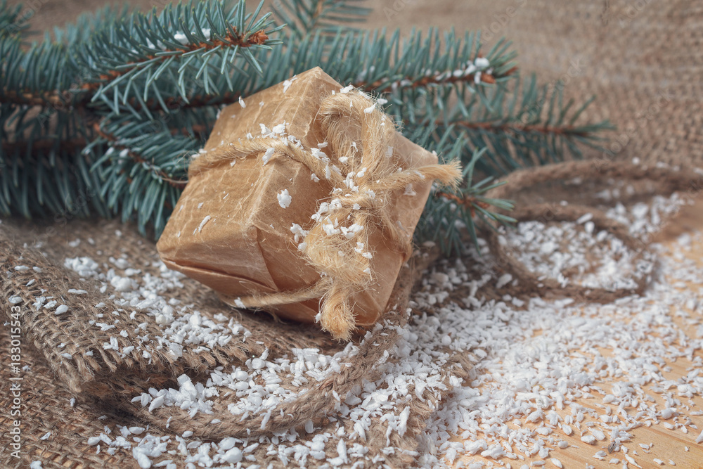 Gift in retro styles and christmas tree covered with snow on a wooden surface Gift in retro styles and christmas tree covered with snow on a wooden surface