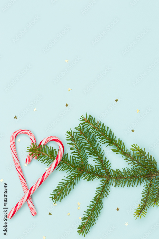 Φωτογραφία Top view on spruce branch and mint hard candy cane striped in Christmas colours in shape of a heart  isolated on a turquoise background